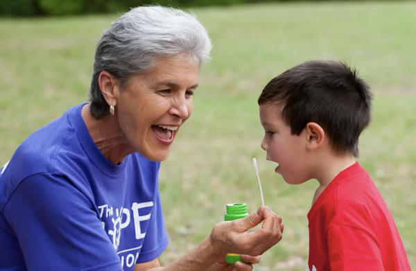 Dr. Karyn Purvis and a camper blow bubbles at Hope Connection. Courtesy of TCU Magazine, Spring 2016.